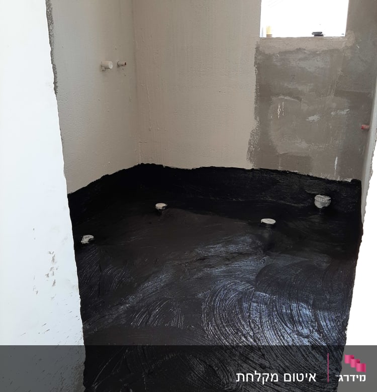 רצפה אטומה בחומר שחור עם צינורות בולטים